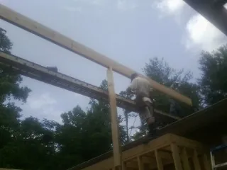 Carpenter setting a ridge beam over a new addition frame — Ice Dam Removal by Roofing Brothers in Roopville