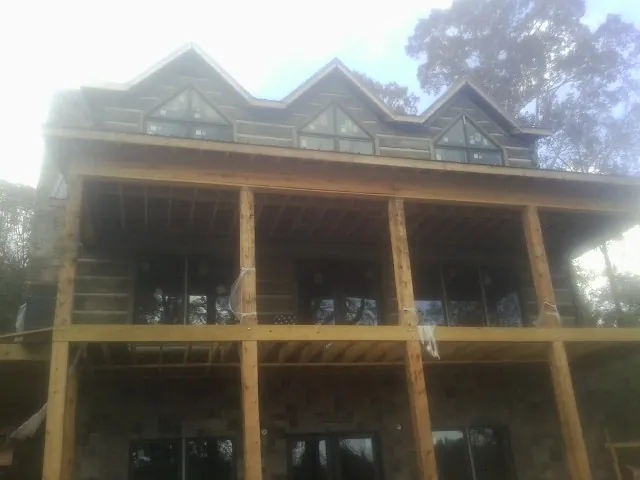 Dormers and porch framing on a large log home under construction — Roof Coating work by our crew in Roopville