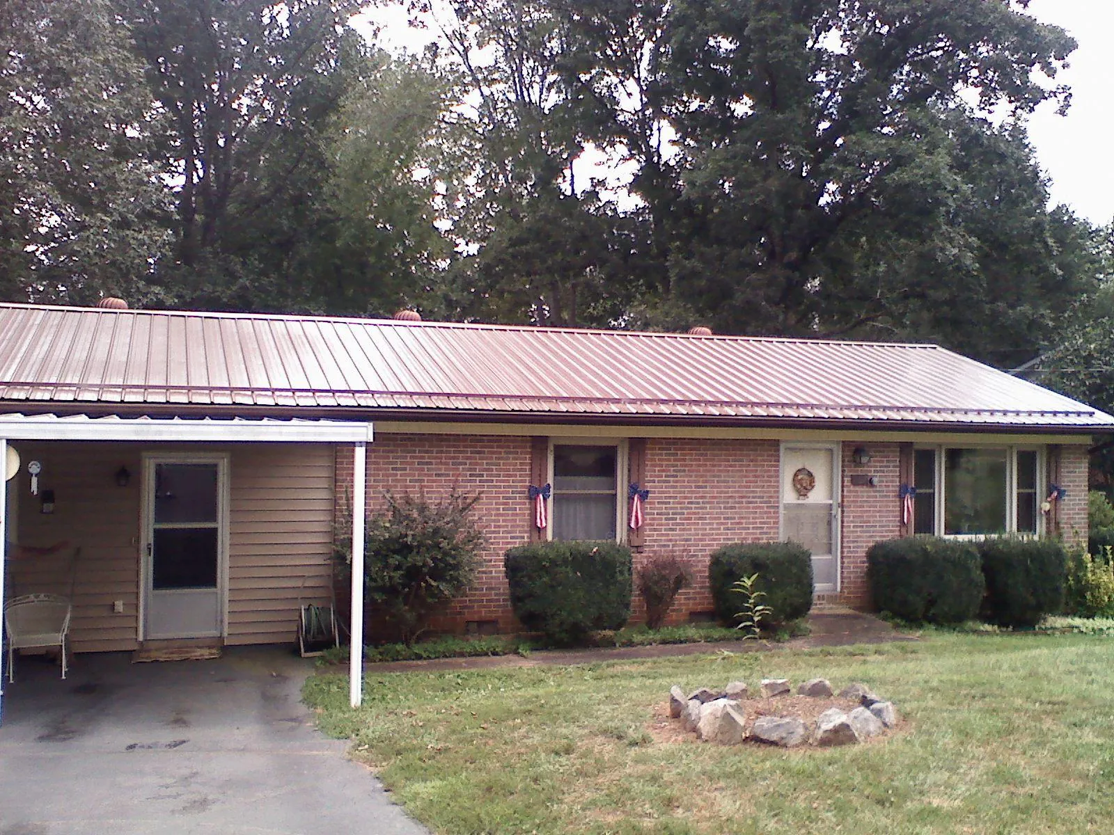 Bronze metal roof and carport on a brick ranch home — Roof Repair work by our crew in Roopville