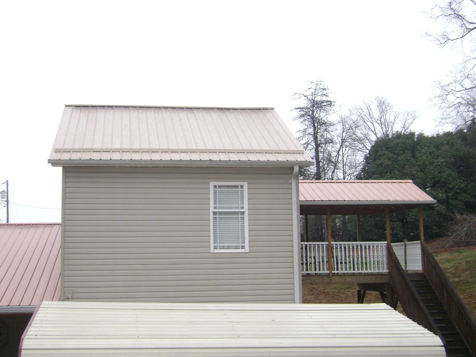 Tan metal roofs on a two story addition and attached porch, from a Roof Replacement job in Roopville