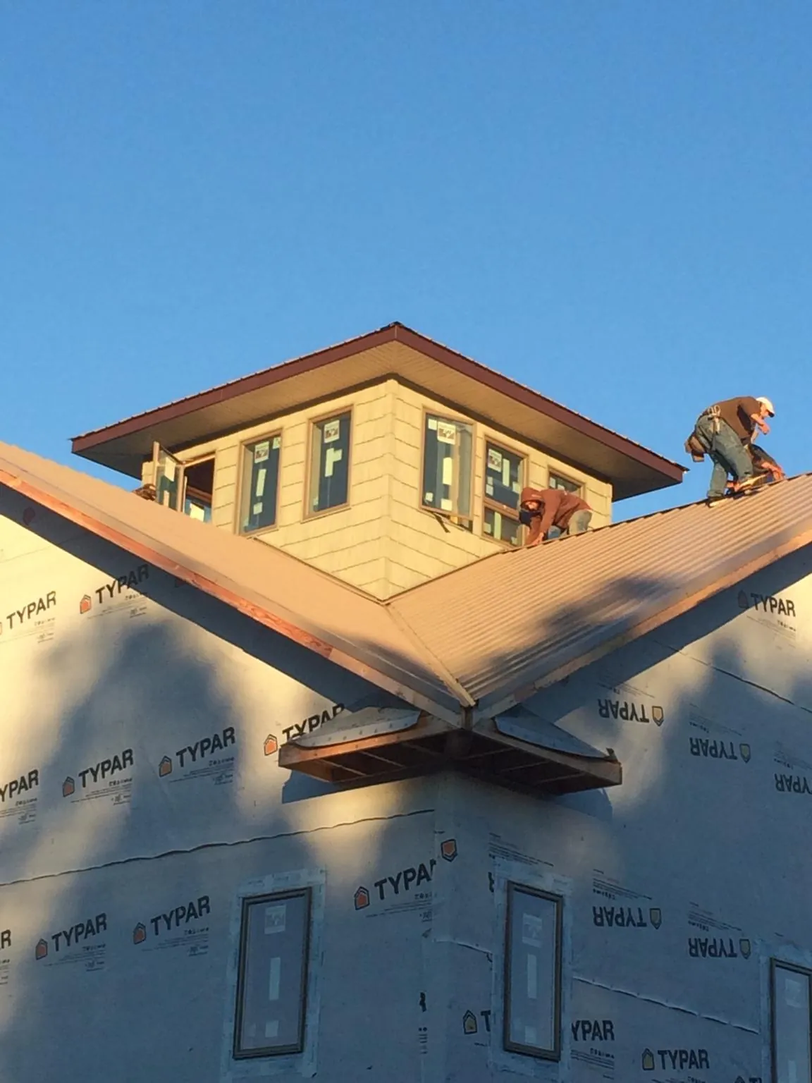 Roofers working around a rooftop cupola on a new metal roof at sunset — Roof Waterproofing in Roopville by Roofing Brothers